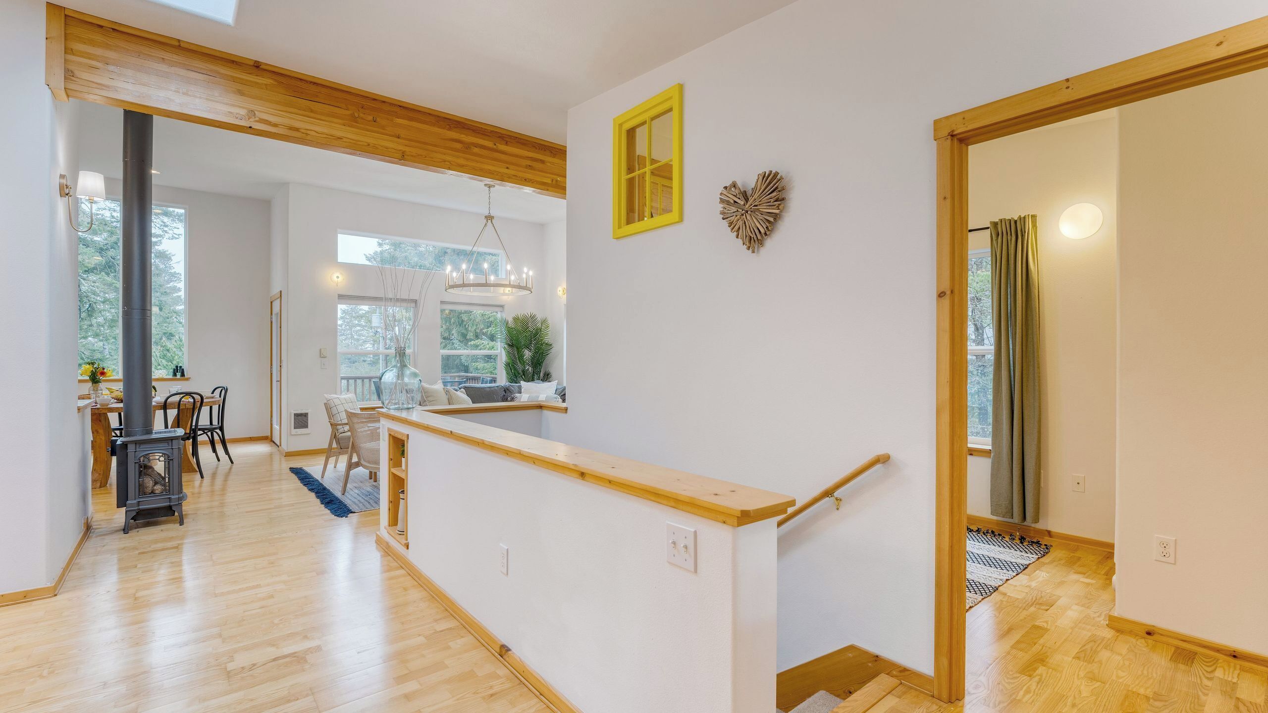 Amplia habitación con techo de madera, zona de comedor con mesa y sillas, un ventanal grande y una escalera con barandilla de madera.