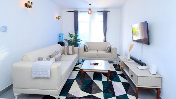 A living room with a sofa, a coffee table, a TV, and a ceiling fan.