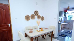 A dining area with a table, chairs, wall decorations, and a view into the kitchen.