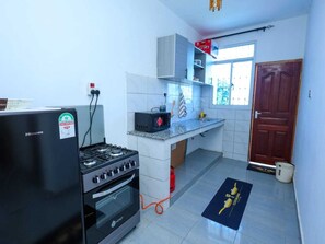 A compact kitchen with a stove, oven, and microwave. - 5 Minutes to the Beach | Stylish 1-Bedroom Apartment in Mombasa (Mombasa)
