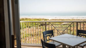 A balcony with a table and chairs, overlooking a beach. - Oceanfront 2BR Villa at Cape Canaveral Beach Resort – Space & Sun (Cape Canaveral)