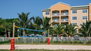 A beach volleyball court with a net, palm trees, and a hotel building in the background. - Oceanfront 2BR Villa at Cape Canaveral Beach Resort – Space & Sun (Cape Canaveral)