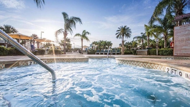 A pool area with a water slide, palm trees, and a lifeguard stand. - Oceanfront 2BR Villa at Cape Canaveral Beach Resort – Space & Sun (Cape Canaveral)