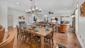 Uma sala de jantar com uma mesa de madeira posta para quatro pessoas, rodeada por cadeiras.