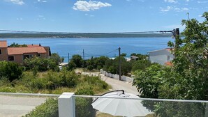Un quartier résidentiel offrant une vue sur une étendue d’eau importante, avec des maisons aux toits recouverts de tuiles rouges et une route asphaltée.