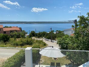 Ein Wohngebiet mit Blick auf ein großes Gewässer, Häuser mit roten Ziegeldächern und einer asphaltierten Straße.