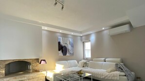 Un salon moderne avec une cheminée, un canapé blanc, une table basse et un tapis gris.