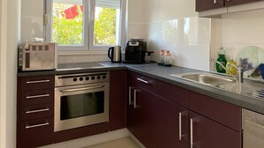 Une cuisine équipée d’une cuisinière, d’un four, d’un évier et d’une fenêtre.