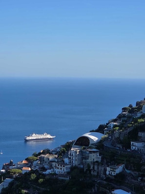 Eine Küstenstadt mit Häusern an einem Hügel mit Blick auf das Meer, ein Kreuzfahrtschiff in der Ferne und eine Kuppelstruktur.