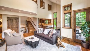 A spacious living area with a staircase, a dining area, and large windows. - Luxury West Vail Duplex - Multi-Level Living Areas (Vail)