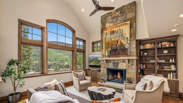 A spacious living room with a fireplace, large windows, and a stone fireplace surround. - Luxury West Vail Duplex - Multi-Level Living Areas (Vail)