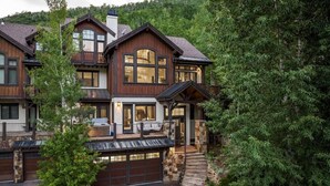 A multi-story house with a garage, a balcony, and a stone staircase leading to the entrance. - Luxury West Vail Duplex - Multi-Level Living Areas (Vail)