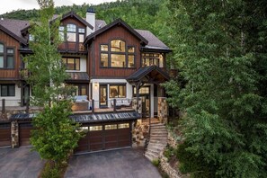 A multi-story house with a garage, a balcony, and a stone staircase leading to the entrance. - Luxury West Vail Duplex - Multi-Level Living Areas (Vail)