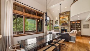 A spacious dining area with a long table, benches, and a view of greenery outside. - Luxury West Vail Duplex - Multi-Level Living Areas (Vail)