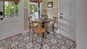 Un coin repas avec une table ronde, quatre chaises, un luminaire suspendu et des carreaux de sol à motifs.