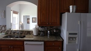 Une cuisine avec des meubles en bois, un réfrigérateur blanc, un plan de travail en granit et un lave-vaisselle.