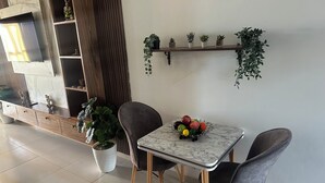 Et spiseområde med et marmorbord, to stole, en skål med frugt og potteplanter.