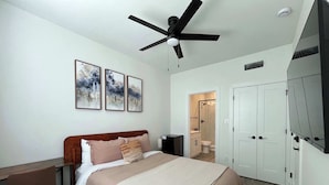A bedroom with a bed, a desk, a ceiling fan, and a bathroom visible through an open door. - Bishop Arts 6BR/6BA townhouse, sleeps 12, parking (Dallas)