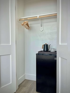 A compact kitchen with a black refrigerator, a wooden drying rack, and a small countertop with a kettle. - Bishop Arts 6BR/6BA townhouse, sleeps 12, parking (Dallas)