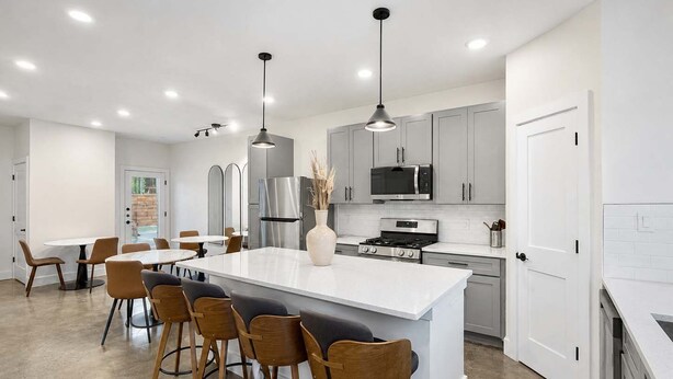 A modern kitchen with a central island, bar stools, stainless steel appliances, and pendant lighting. - Bishop Arts 6BR/6BA townhouse, sleeps 12, parking (Dallas)