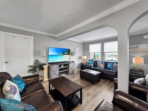 Ein Wohnzimmer mit Fernseher, Sofas, einem Couchtisch und einem großen Fenster.