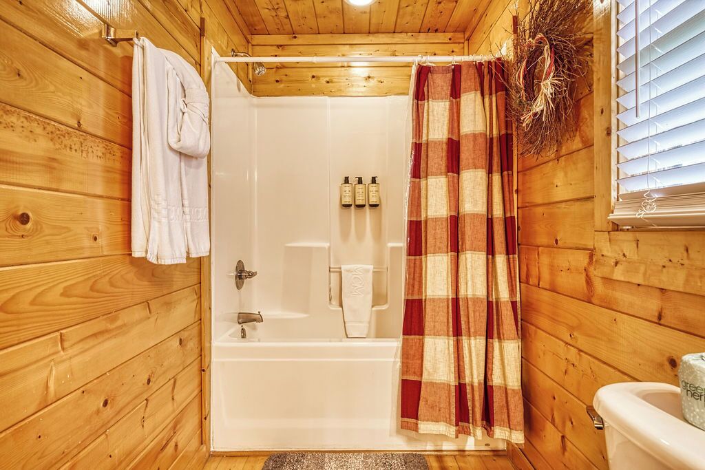Ein Badezimmer in einer Holzhütte mit Dusche, Toilette und Handtuchhalter.