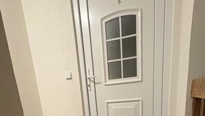A white door with a glass panel, a doormat, and a tiled floor.