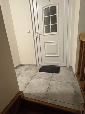 A white door with a glass panel, a doormat, and a tiled floor.