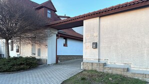 A building with a tiled roof, a stone pathway, and a grassy area.