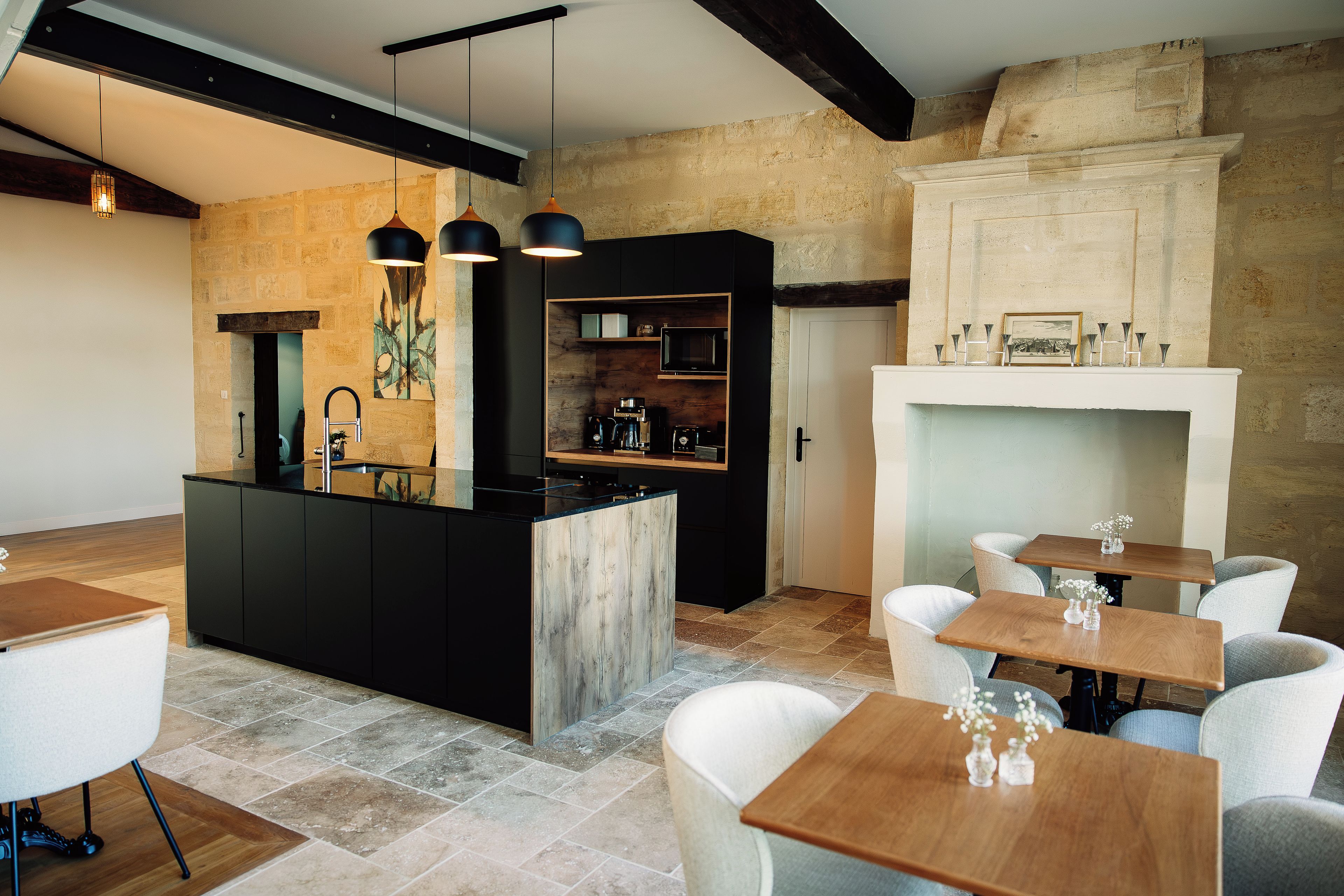 A modern kitchen with a central island, black cabinetry, and pendant lighting.