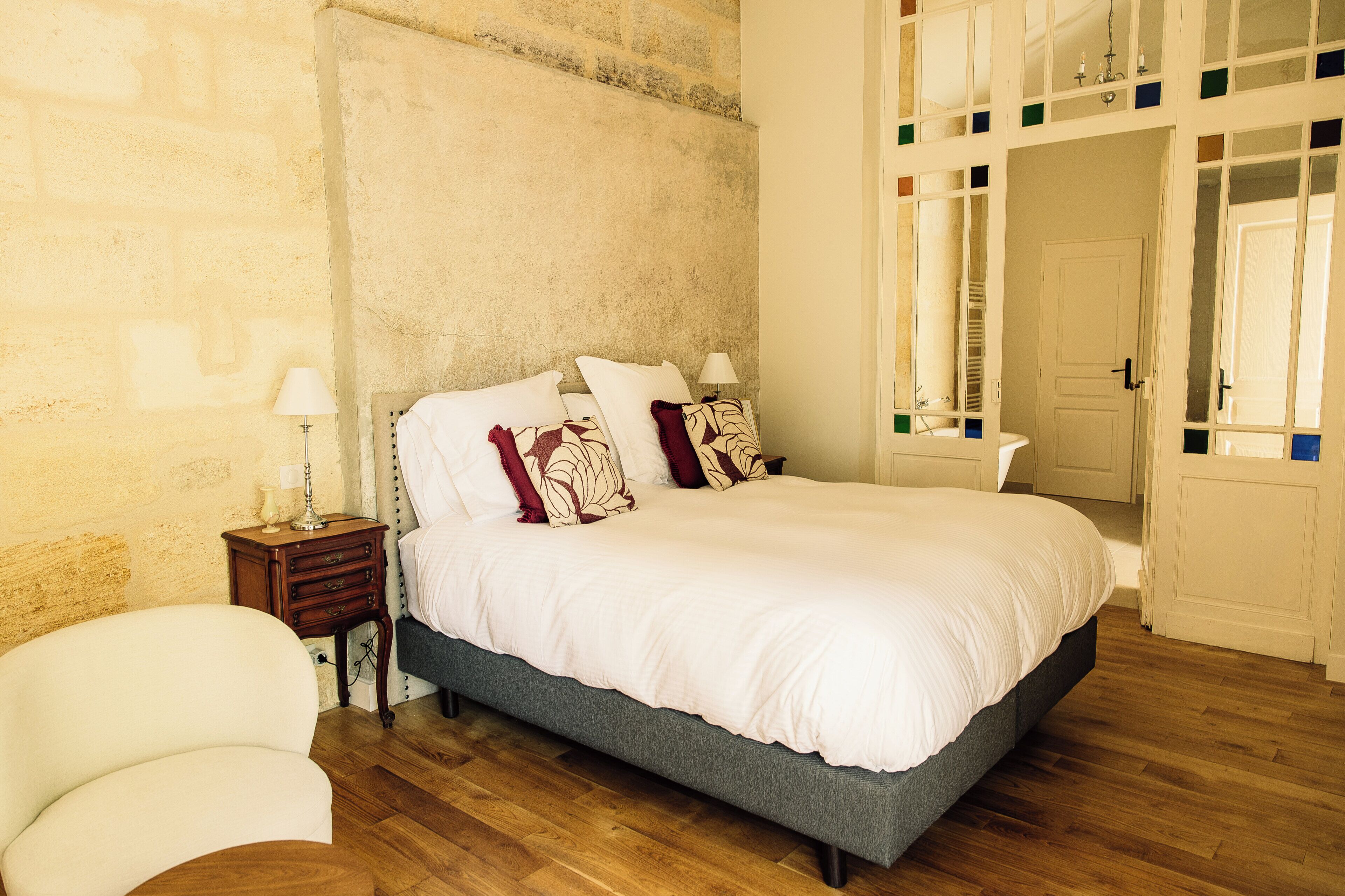 Quarto com cama, mesas de cabeceira, uma cadeira e um guarda-roupa.