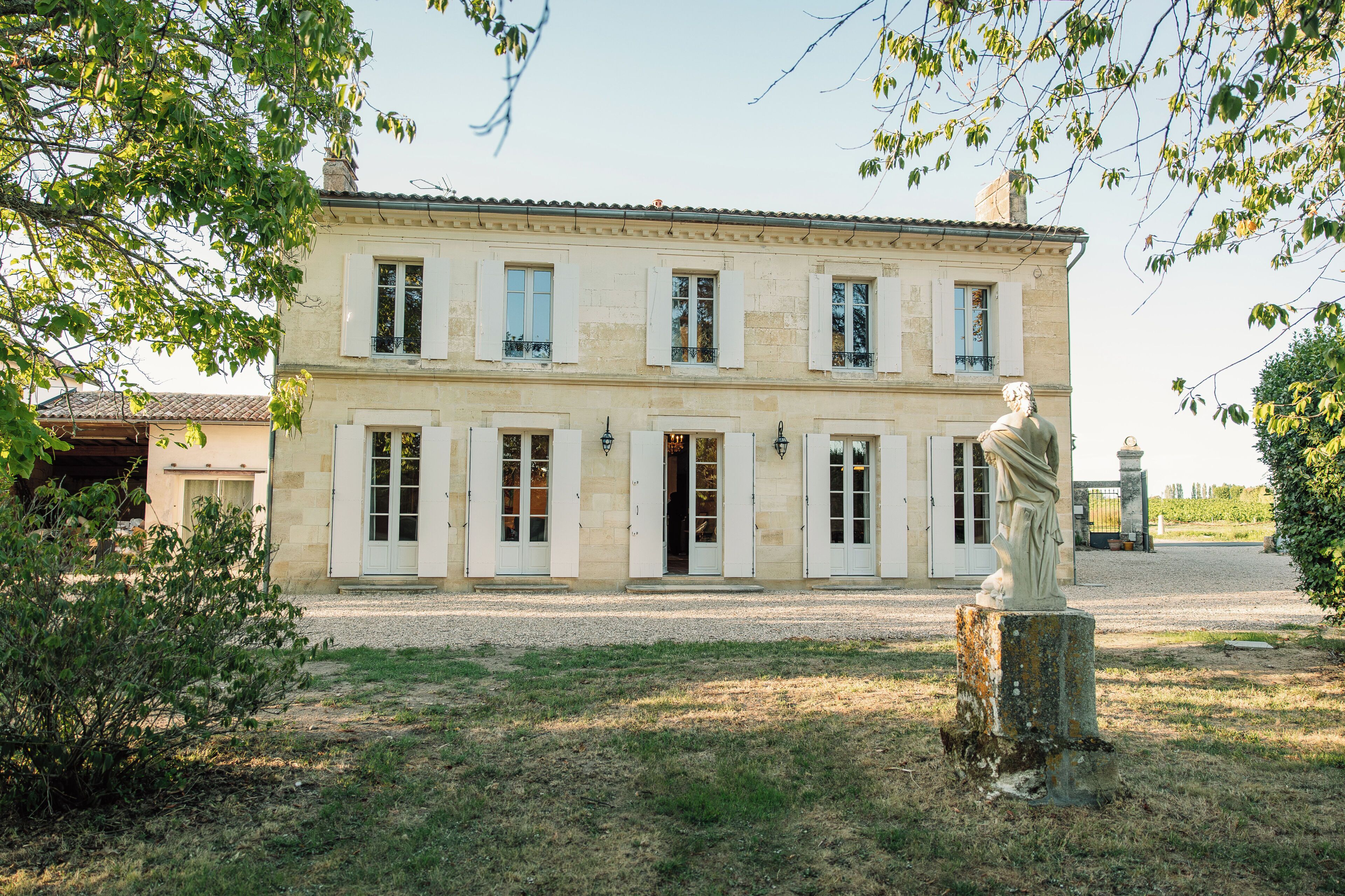 Un bâtiment à deux étages doté d’une façade symétrique, de grandes fenêtres avec volets et d’une entrée centrale.