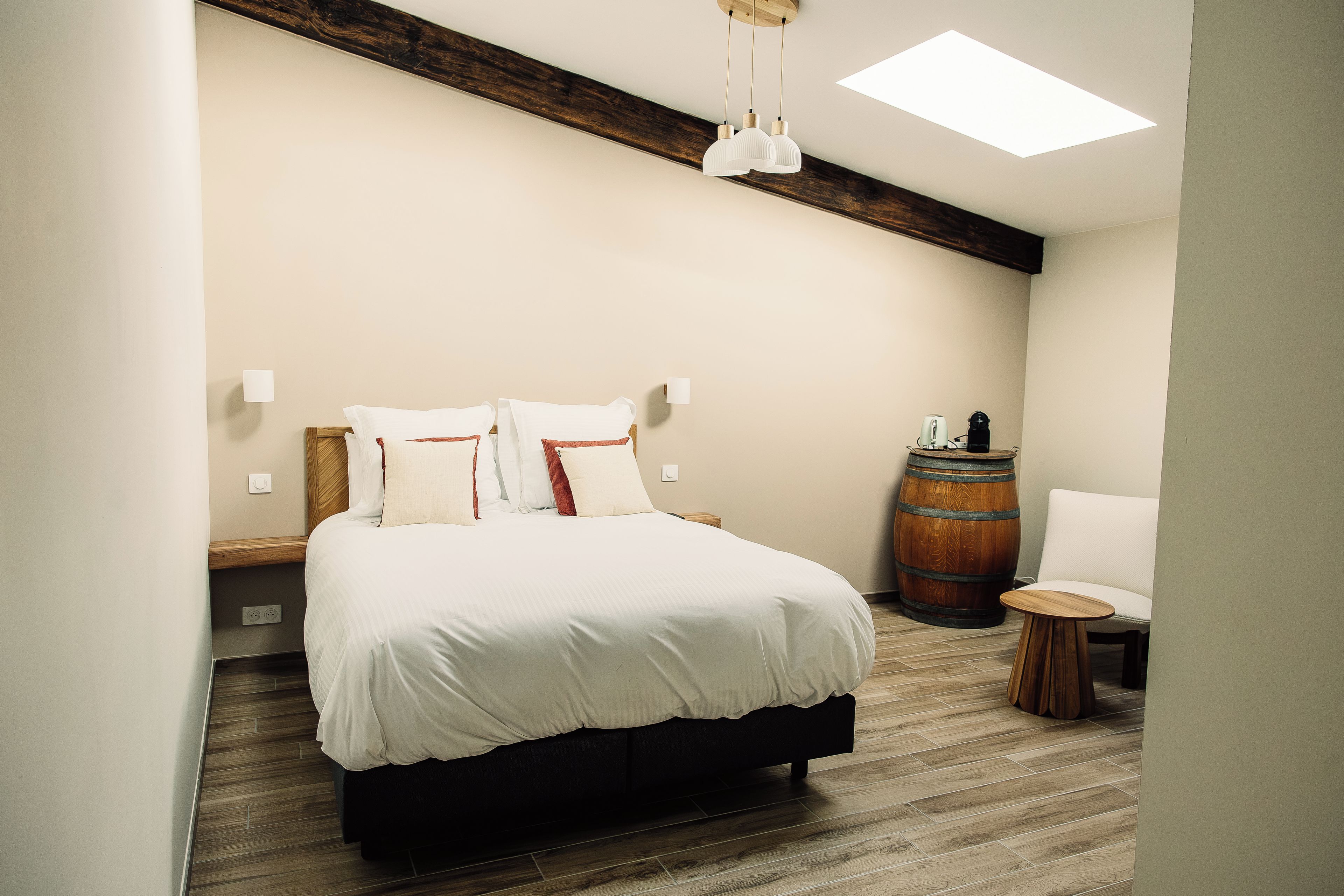 Une chambre avec un lit, une chaise, un tonneau en bois et une petite table.