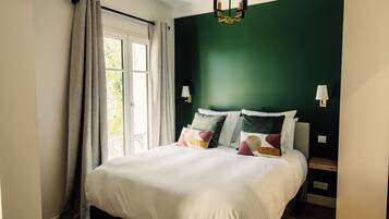 Un dormitorio con cama, cortinas, una ventana y una pared verde.
