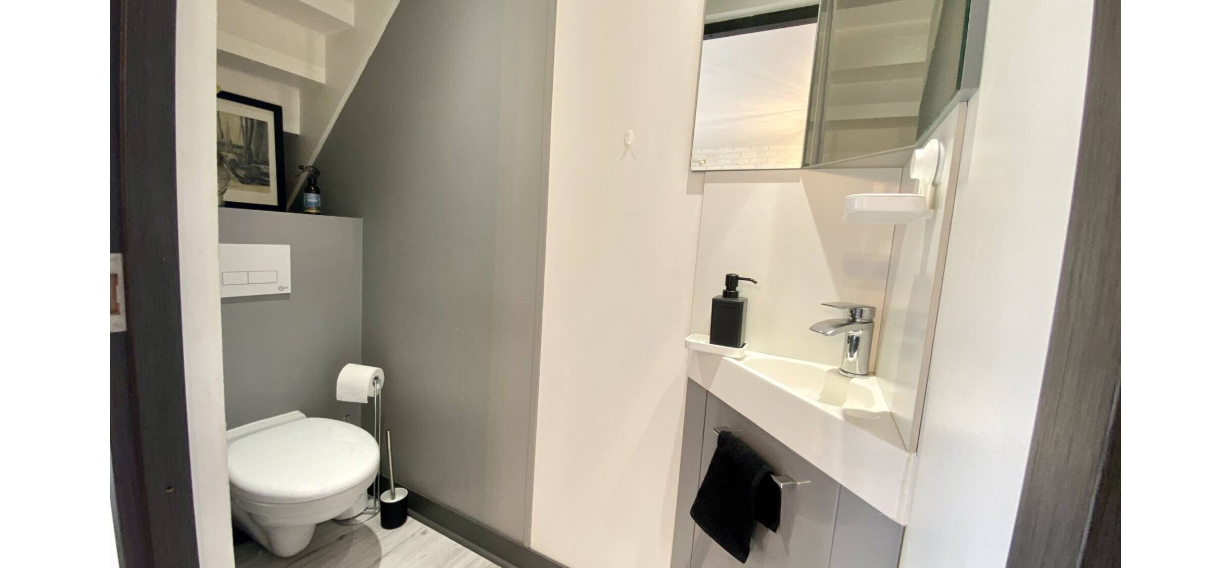 Un baño con inodoro, lavamanos con espejo y barra para toallas.