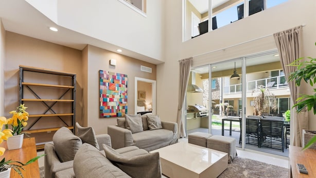 A spacious living area with a sofa set, a coffee table, and a bookshelf. - Designer 4BR Getaway, Sleek Laminate Floors (Kissimmee)