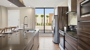 Una cocina moderna con una isla grande, electrodomésticos de acero inoxidable y vistas al exterior.