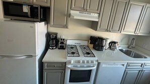 Eine kompakte Küche mit Mikrowelle, Kaffeemaschine, Herd, Backofen und Geschirrspüler.