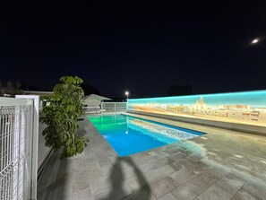 Una piscina con un murale raffigurante un panorama urbano, una recinzione in metallo e una pianta in vaso.