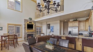 A spacious dining area with a fireplace, a kitchen with wooden cabinets, and a chandelier. - Lakefront Luxury Retreat LS61 | Hot Tub | Pool (Huntsville)