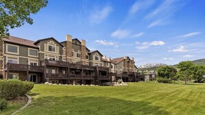 A multi-story residential building with a well-maintained lawn and a mountain backdrop. - Lakefront Luxury Retreat LS61 | Hot Tub | Pool (Huntsville)