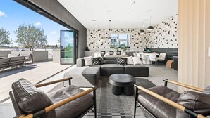 Et moderne loungeområde med lædersofaer, et rundt sofabord og et spiseområde med hvide stole.