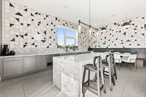 A modern kitchen with a geometric tile backsplash, a large island with bar stools, and a dining area with a table and chairs. - Skyline Luxe, Downtown LA, Epic Rooftop Views, Walk to Dodger Stadium (Los Angeles)