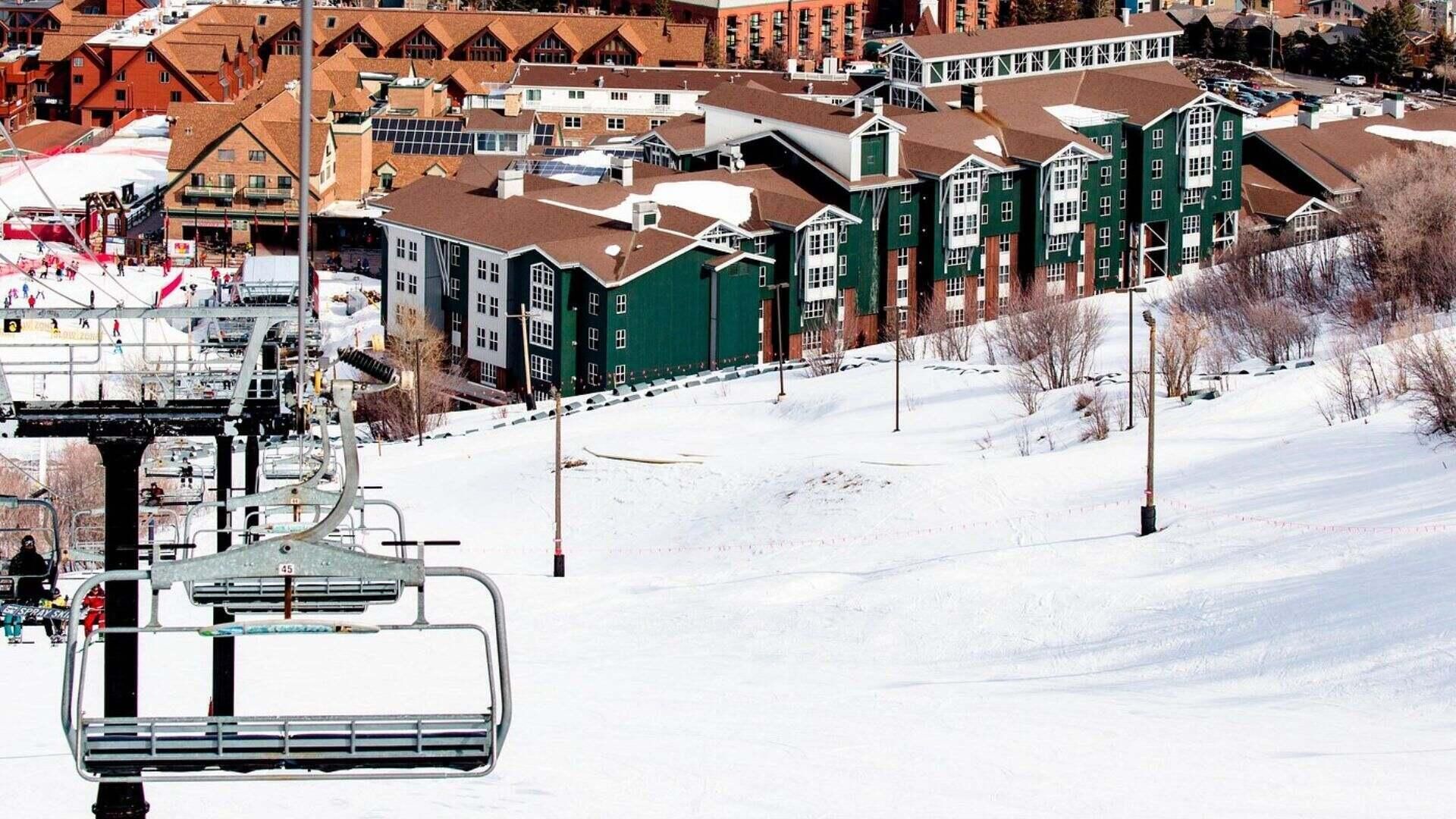 A ski lift chair with a metal frame and a number 45 on it, overlooking a snowy slope with buildings in the background.