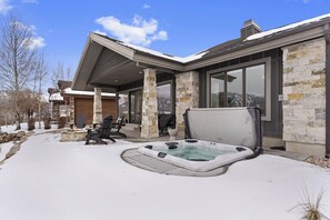 A modern house with a hot tub, stone exterior, and a covered patio. - Nordic View Haven | Golf | Mtn View | Hot Tub (Eden)