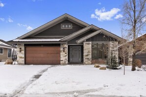 A residential house with a garage, stone exterior, and a snow-covered driveway. - Nordic View Haven | Golf | Mtn View | Hot Tub (Eden)