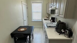 A compact kitchen with a dining table, a coffee maker, and a microwave. - Fully private 1bed apt brookline (Brookline)