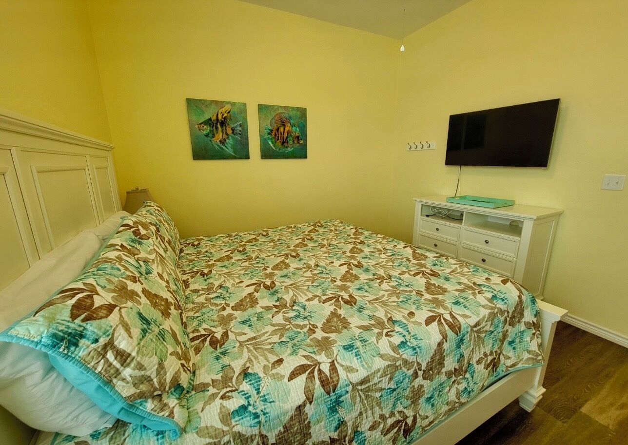Ein Schlafzimmer mit einem Bett, einem Fernseher und zwei Bildern an der Wand.