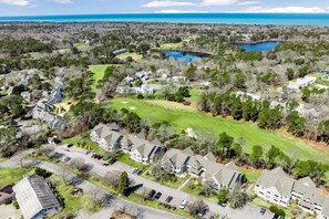 An aerial view of a residential area with houses, a golf course, and a lake.