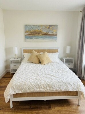A neatly made bed with a white headboard and two bedside tables, each with a lamp.